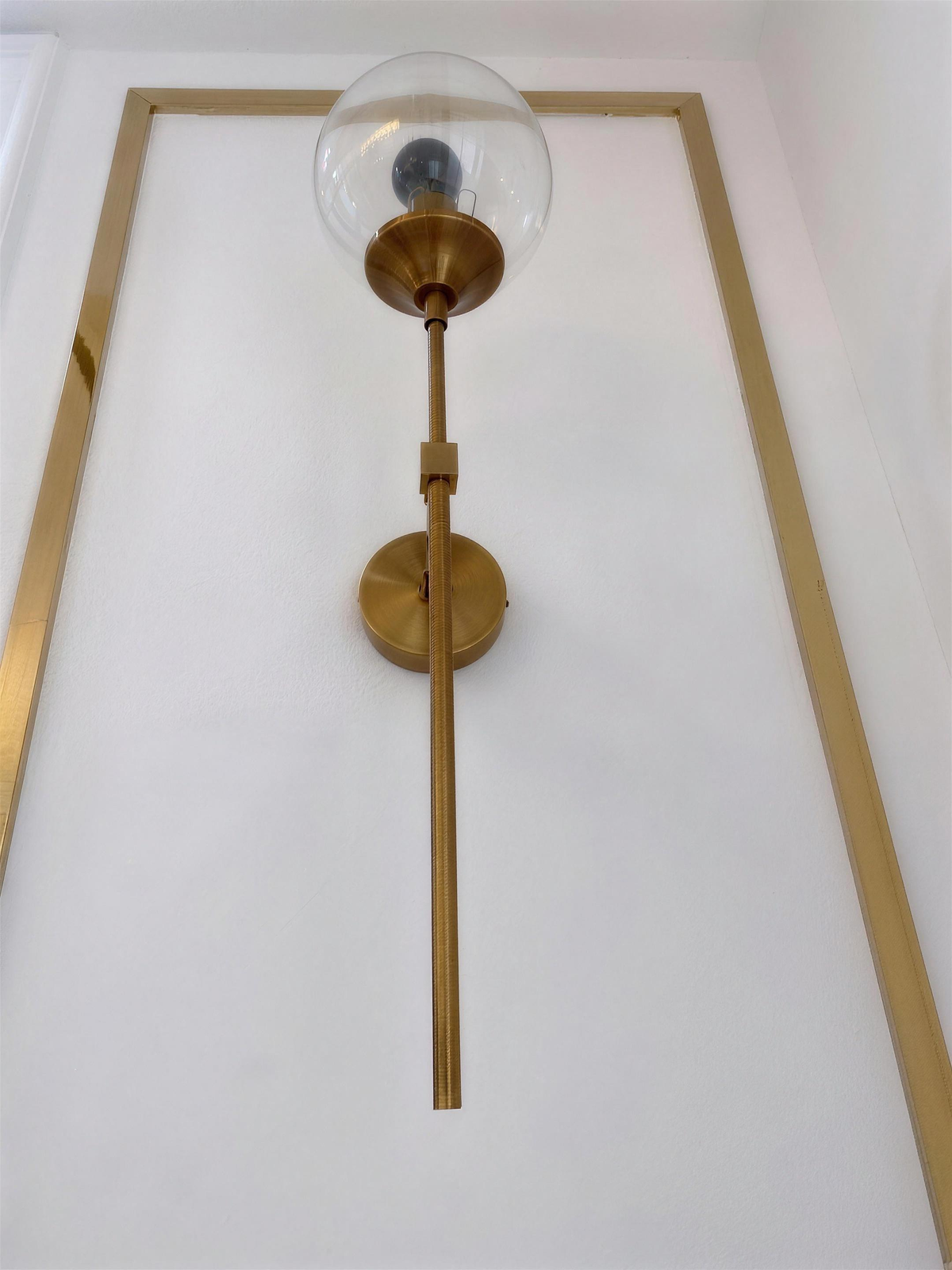 Marlow gold wall light switched off against panelled wall - Hestia + Co.