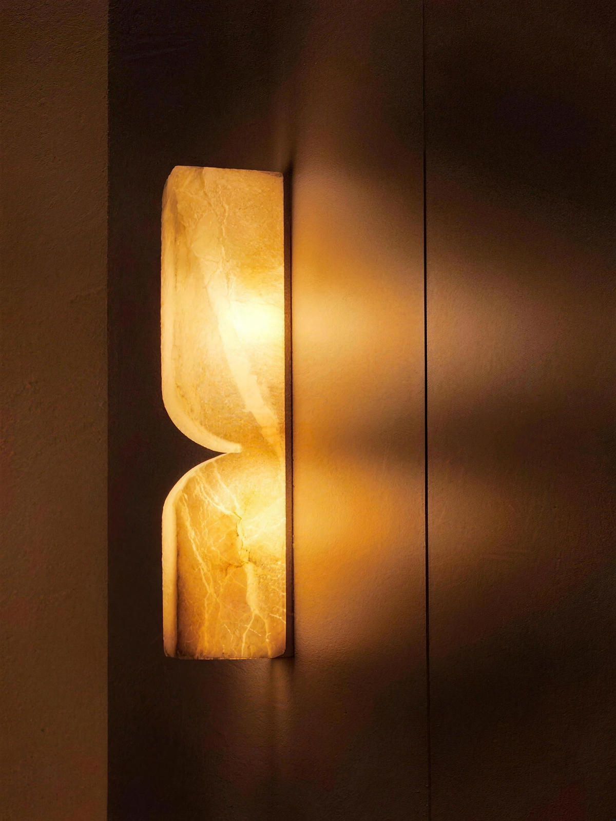 Close-up of the Ronda marble wall light glowing beside a brass panel - Hestia + Co.
