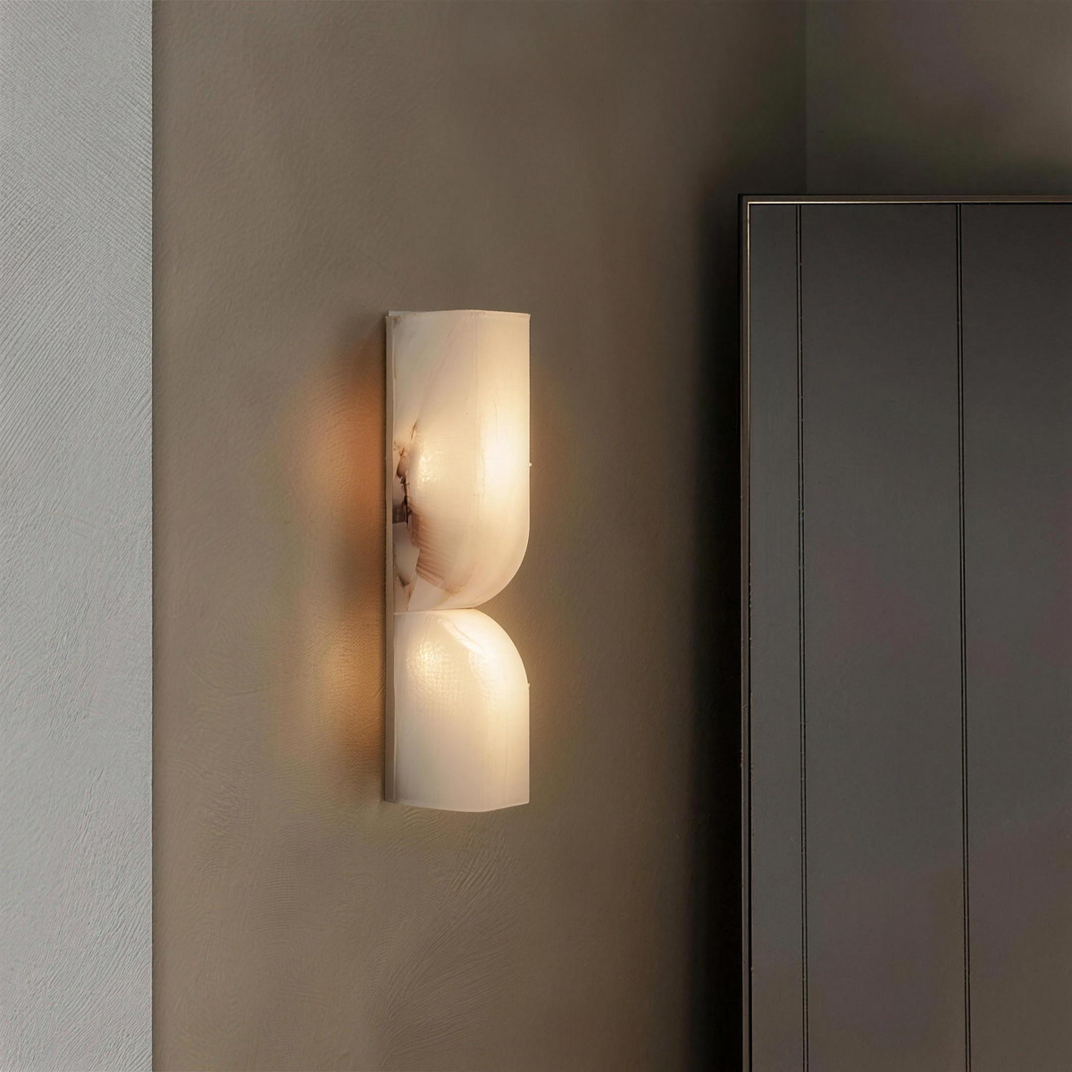 Ronda marble wall light lit on a taupe plaster wall beside a wardrobe - Hestia + Co.