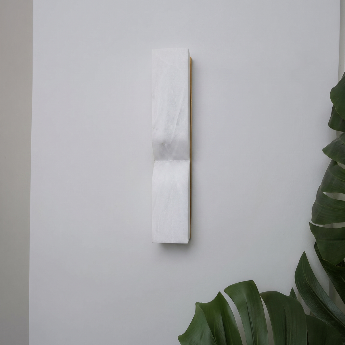 Ronda marble wall light switched off on a white wall beside a monstera - Hestia + Co.