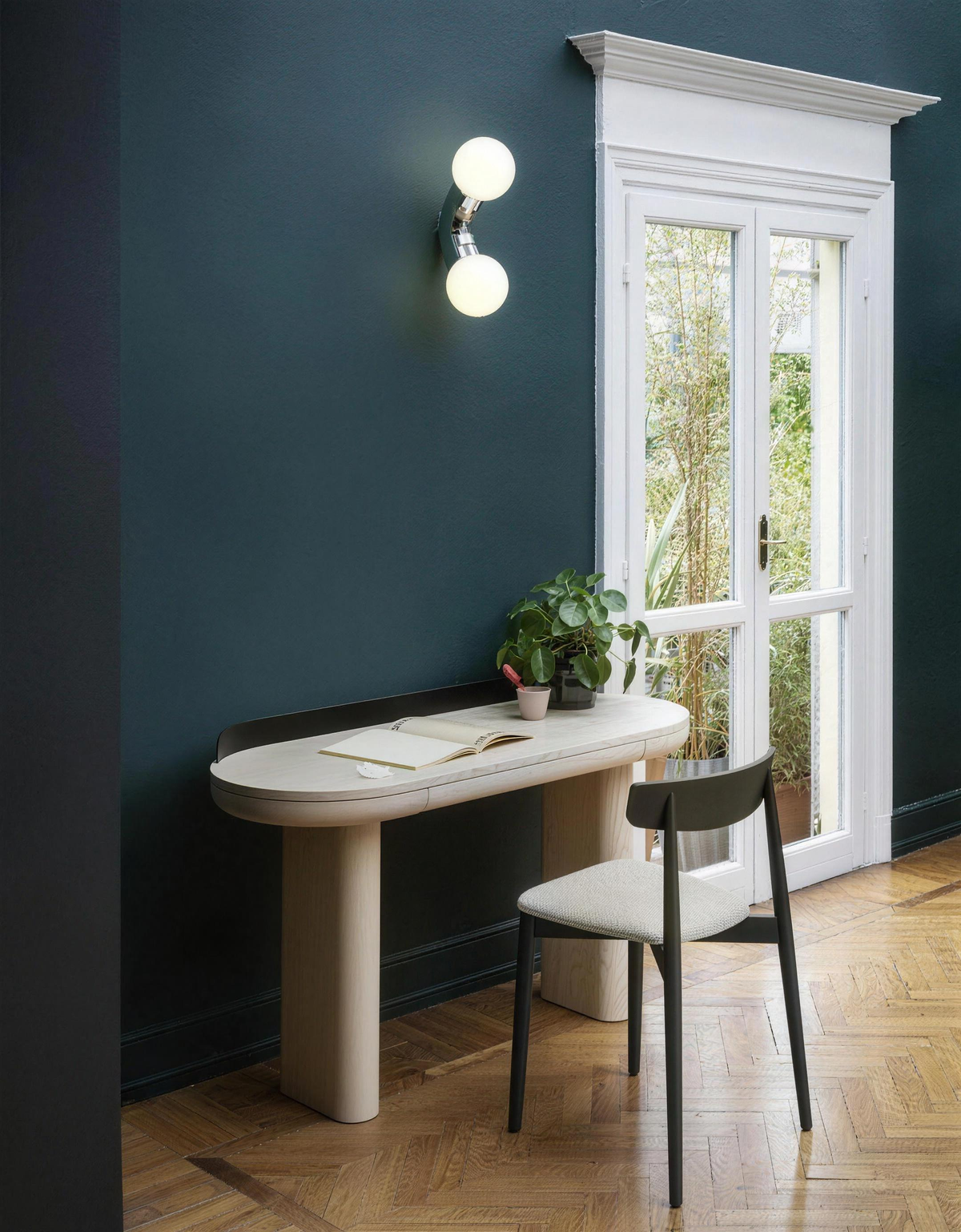 Como wall light switched on above a desk on a teal wall - Hestia + Co.