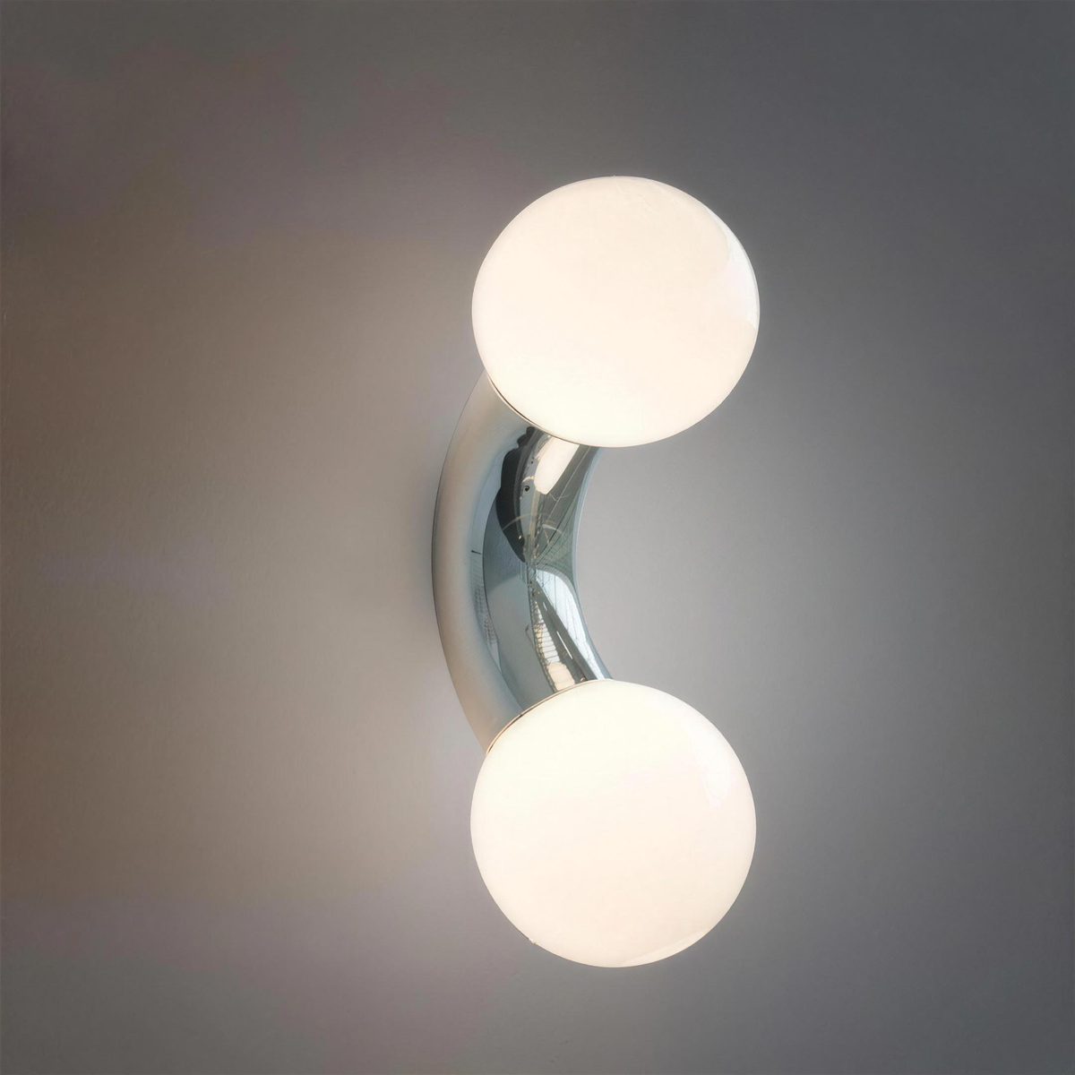Como chrome wall light with two frosted globes, lit on a grey wall - Hestia + Co.