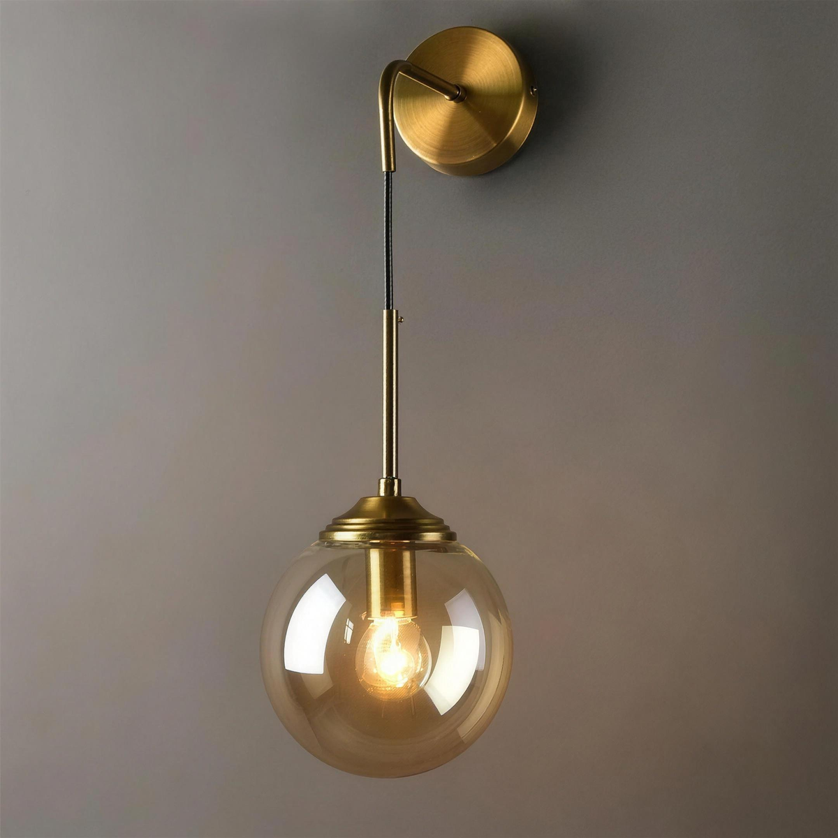 Marlow Style B gold wall light with amber globe hanging below the arm - Hestia + Co.