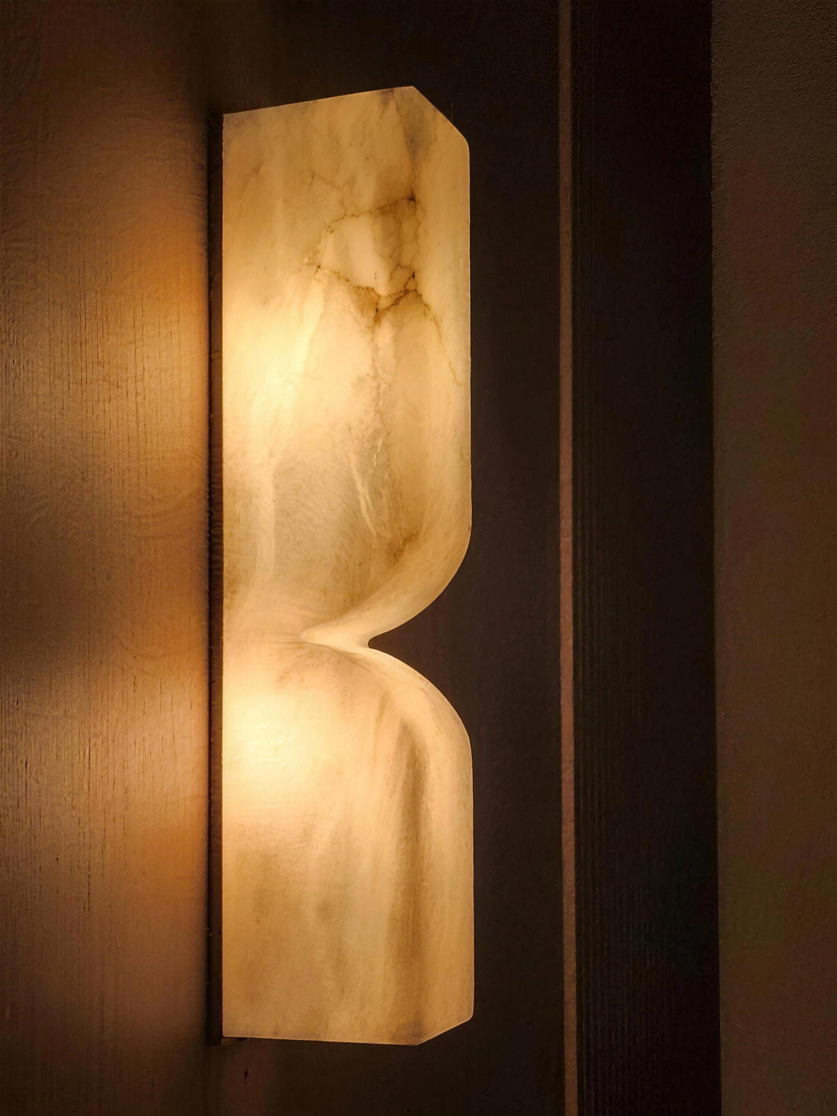 Close-up of the Ronda marble wall light glowing against dark wood - Hestia + Co.